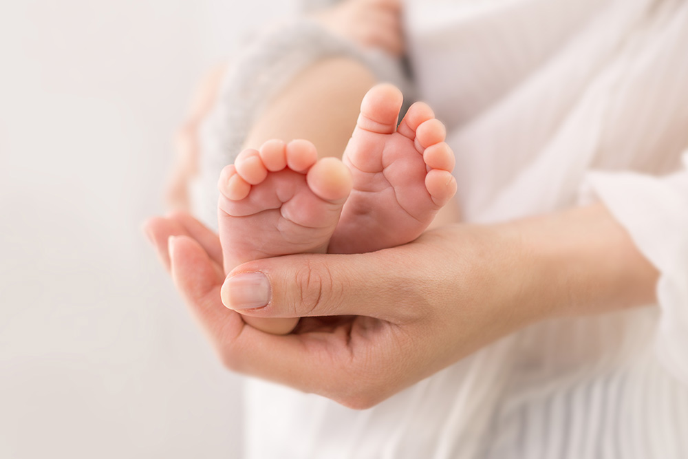 Frauenhände halten Kinderfüße in der Hand